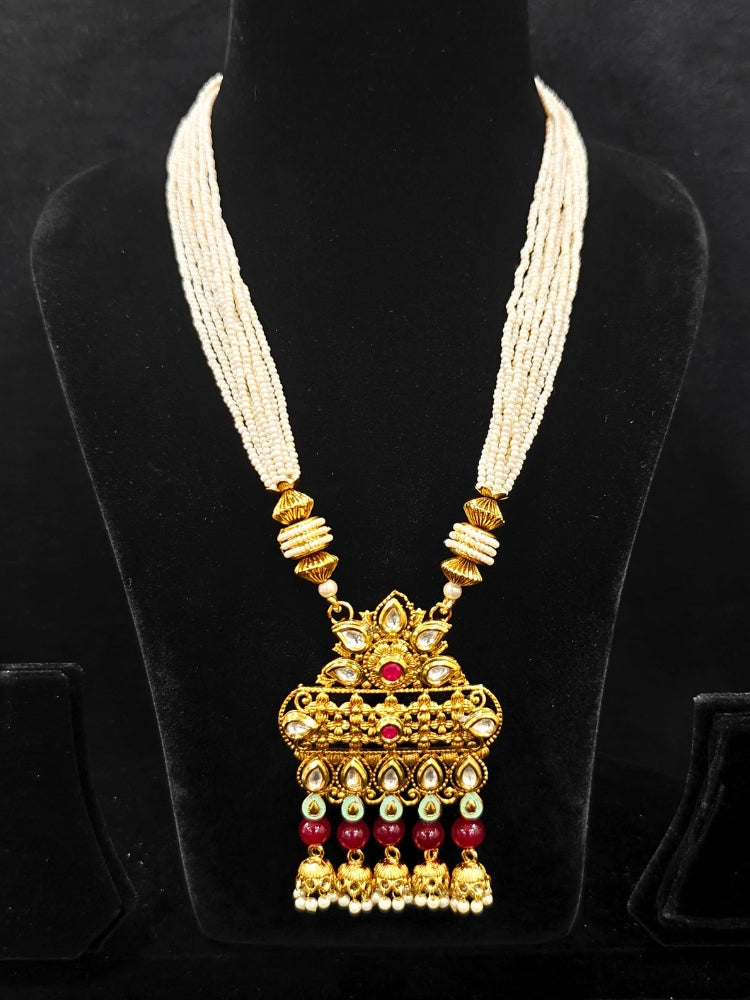 Close-up of an ornate traditional Rajwadi gold Long jewellery set and earrings with Kundan, Coloured Beads and pearls. Wedding guest styling a Rajwadi artificial necklace with a Saree. Festive look completed with a luxury Rajwadi imitation necklace.