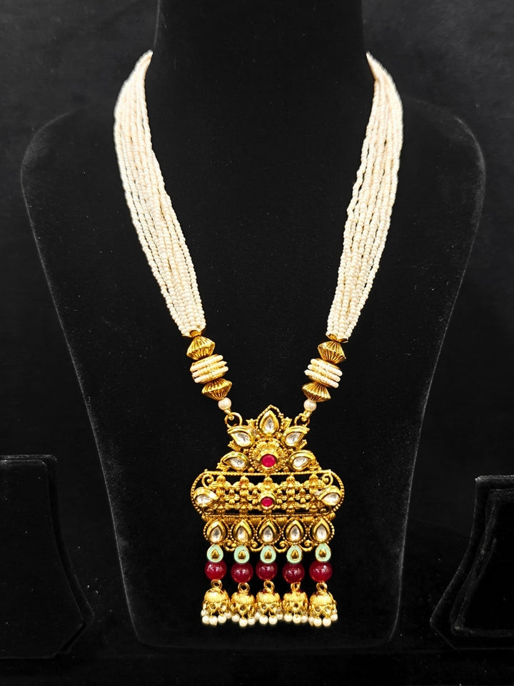 Close-up of an ornate traditional Rajwadi gold Long jewellery set and earrings with Kundan, Coloured Beads and pearls. Wedding guest styling a Rajwadi artificial necklace with a Saree. Festive look completed with a luxury Rajwadi imitation necklace.