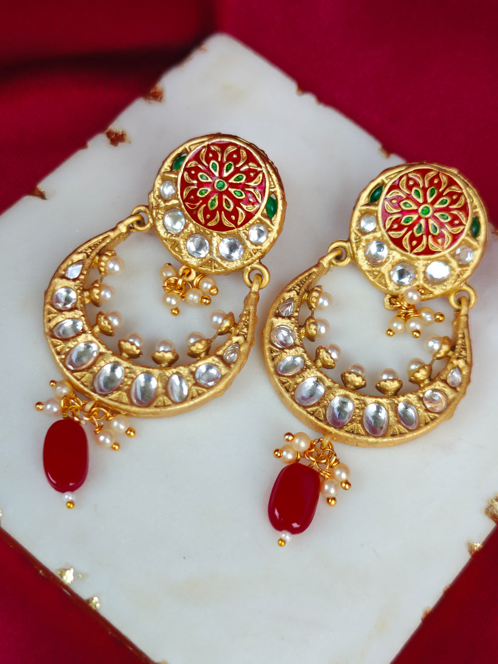 Close-up of an ornate traditional Red Meenakari gold Earrings with Pearls, Kundan and Meenakari. Festive saree look completed with premium imitation Meenakari earrings. Perfect Meenakari Earring set for weddings and festivals.