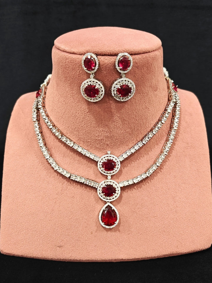 An elegant artificial diamond necklace with red colored stone and matching earrings. This premium artificial diamond jewelry set is perfect for special occasions, from Indian weddings to engagement parties, offering sophisticated glamour without the high price tag.
