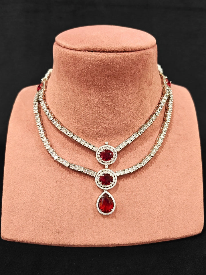 An elegant artificial diamond necklace with red colored stone and matching earrings. This premium artificial diamond jewelry set is perfect for special occasions, from Indian weddings to engagement parties, offering sophisticated glamour without the high price tag.