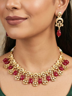 Close-up of a woman wearing an ornate traditional (Gold Polish) Collar Red jewellery set and earrings with Polki, Meenakari and Red Tumble Beads.Festive saree look completed with a Polki artificial jewelry set. Woman wearing a lightweight Polki jewelry set for long wedding functions.