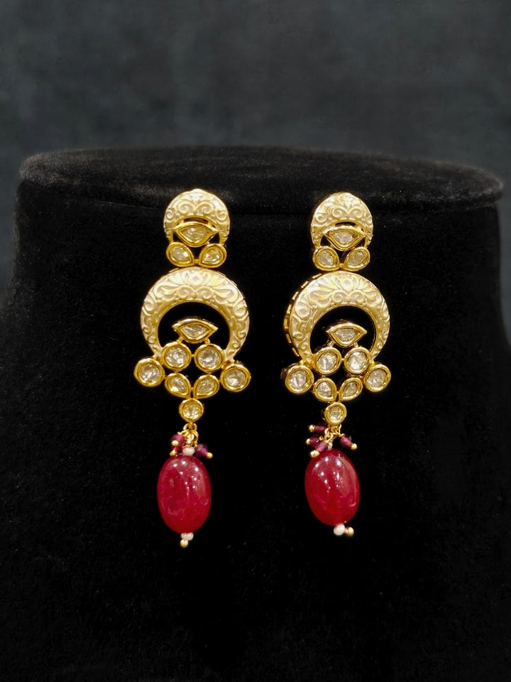 Close-up of an ornate traditional (Gold Polish) Collar Red jewellery set and earrings with Polki, Meenakari and Red Tumble Beads.Festive saree look completed with a Polki artificial jewelry set. Woman wearing a lightweight Polki jewelry set for long wedding functions.