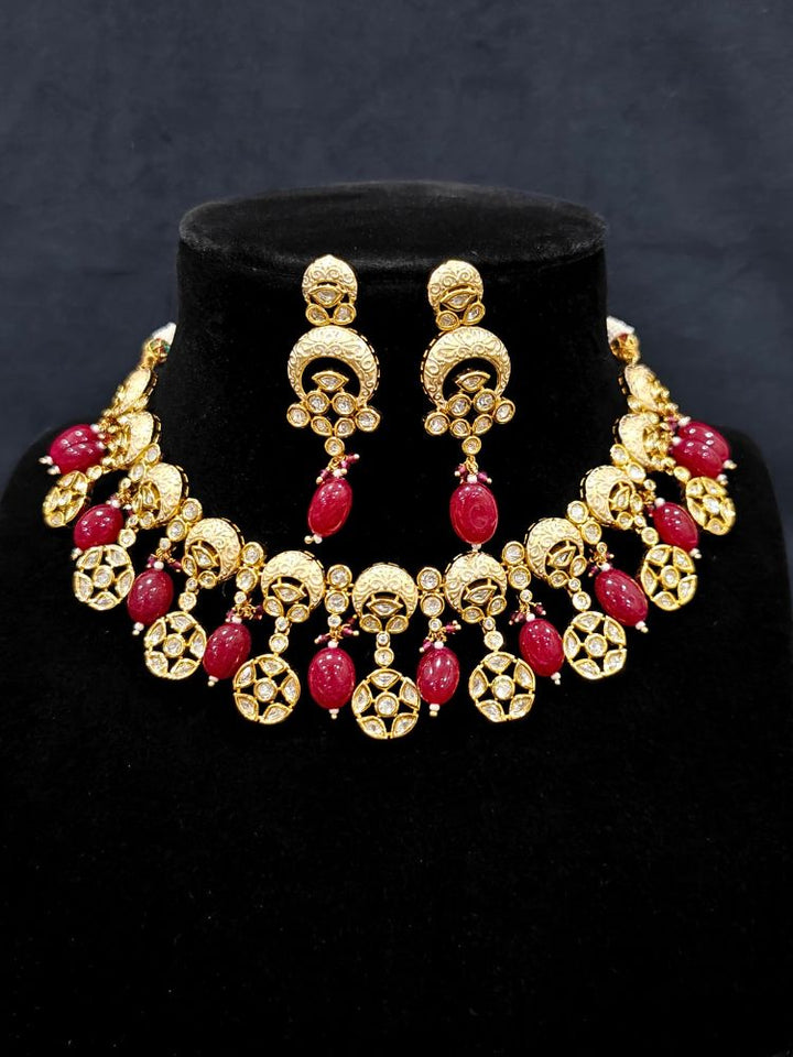 Close-up of an ornate traditional (Gold Polish) Collar Red jewellery set and earrings with Polki, Meenakari and Red Tumble Beads.Festive saree look completed with a Polki artificial jewelry set. Woman wearing a lightweight Polki jewelry set for long wedding functions.