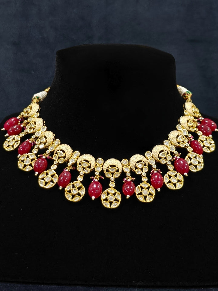 Close-up of an ornate traditional (Gold Polish) Collar Red jewellery set and earrings with Polki, Meenakari and Red Tumble Beads.Festive saree look completed with a Polki artificial jewelry set. Woman wearing a lightweight Polki jewelry set for long wedding functions.