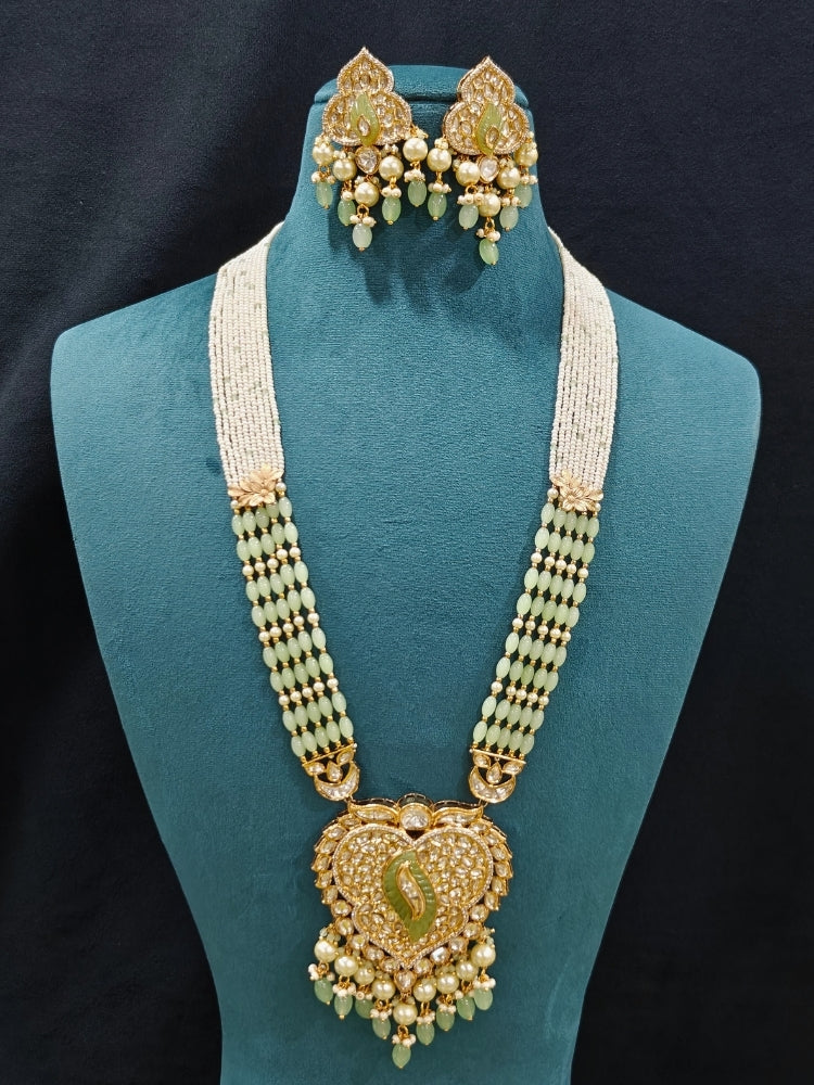 Close-up of an ornate traditional (Gold Polish) Mint Green Long jewellery set and earrings with Polki, American Diamond Tumble Beads and Pearls. Woman wearing trending Polki artificial jewelry for the wedding season in India. Wedding guest outfit styled with an elegant Polki necklace set.