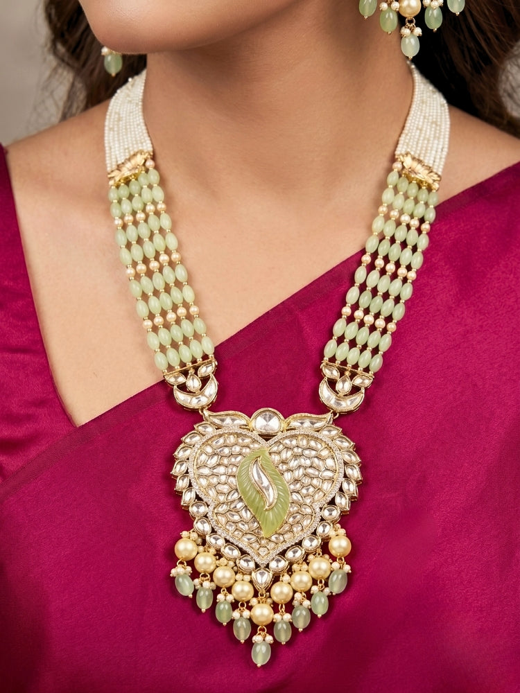 Close-up of a woman wearing an ornate traditional (Gold Polish) Mint Green Long jewellery set and earrings with Polki, American Diamond Tumble Beads and Pearls. Woman wearing trending Polki artificial jewelry for the wedding season in India. Wedding guest outfit styled with an elegant Polki necklace set.