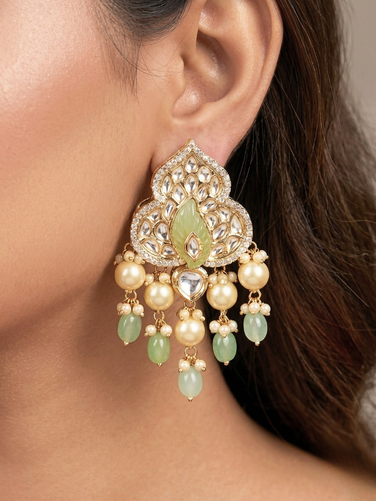Close-up of a woman wearing an ornate traditional (Gold Polish) Mint Green Long jewellery set and earrings with Polki, American Diamond Tumble Beads and Pearls. Woman wearing trending Polki artificial jewelry for the wedding season in India. Wedding guest outfit styled with an elegant Polki necklace set.