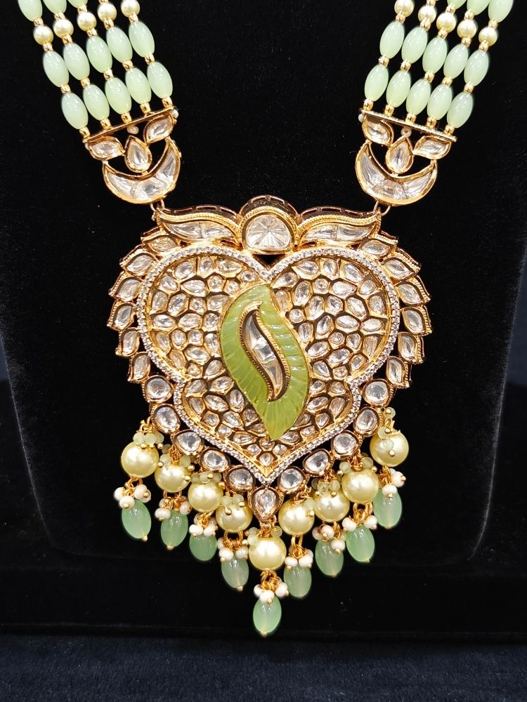 Close-up of an ornate traditional (Gold Polish) Mint Green Long jewellery set and earrings with Polki, American Diamond Tumble Beads and Pearls. Woman wearing trending Polki artificial jewelry for the wedding season in India. Wedding guest outfit styled with an elegant Polki necklace set.
