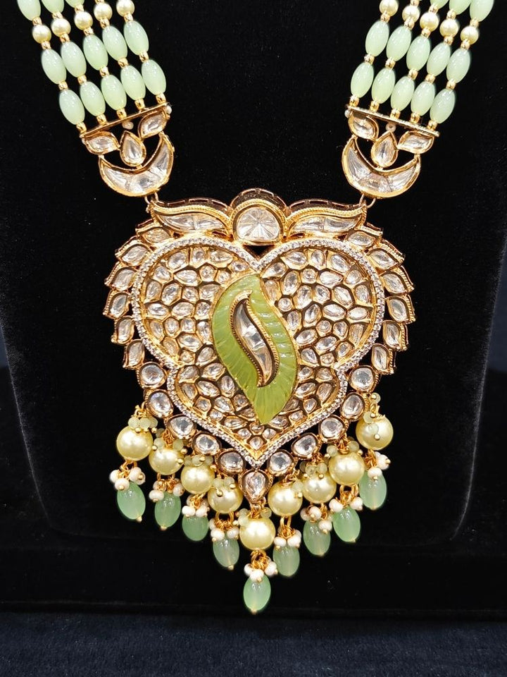 Close-up of an ornate traditional (Gold Polish) Mint Green Long jewellery set and earrings with Polki, American Diamond Tumble Beads and Pearls. Woman wearing trending Polki artificial jewelry for the wedding season in India. Wedding guest outfit styled with an elegant Polki necklace set.