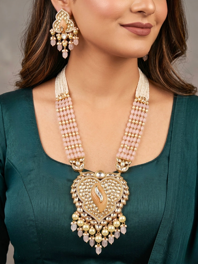 Close-up of a women wearing an ornate traditional (Gold Polish) Mint Pink Long jewellery set and earrings with Polki, American Diamond Tumble Beads and Pearls. Woman wearing trending Polki artificial jewelry for the wedding season in India. Wedding guest outfit styled with an elegant Polki necklace set.