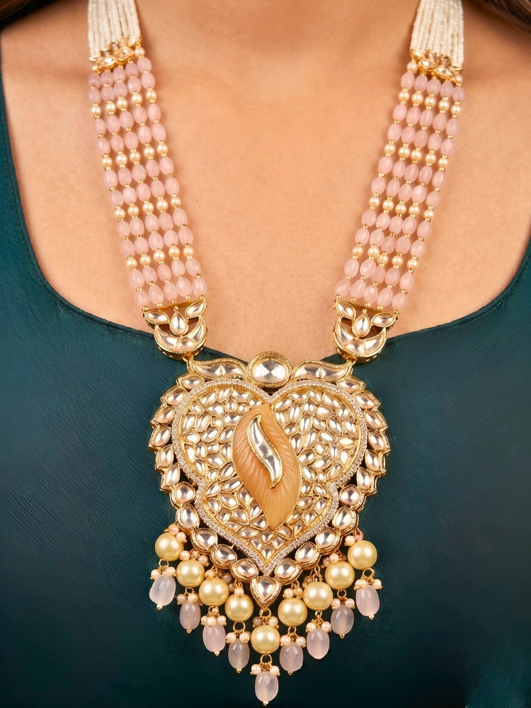 Close-up of a women wearing an ornate traditional (Gold Polish) Mint Pink Long jewellery set and earrings with Polki, American Diamond Tumble Beads and Pearls. Woman wearing trending Polki artificial jewelry for the wedding season in India. Wedding guest outfit styled with an elegant Polki necklace set.