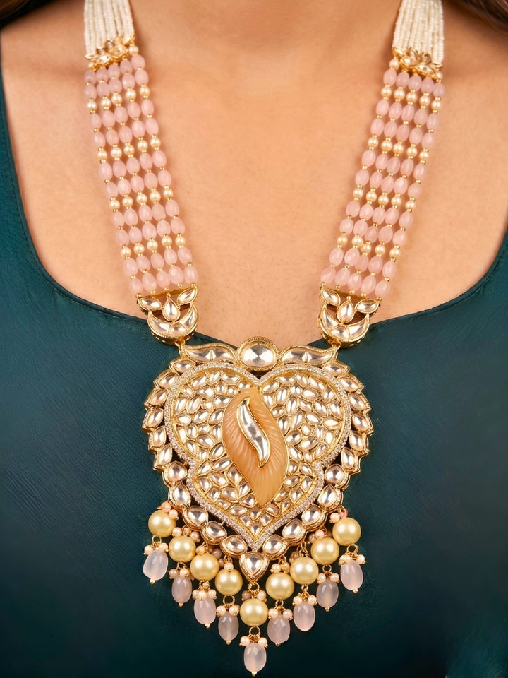 Close-up of a women wearing an ornate traditional (Gold Polish) Mint Pink Long jewellery set and earrings with Polki, American Diamond Tumble Beads and Pearls. Woman wearing trending Polki artificial jewelry for the wedding season in India. Wedding guest outfit styled with an elegant Polki necklace set.