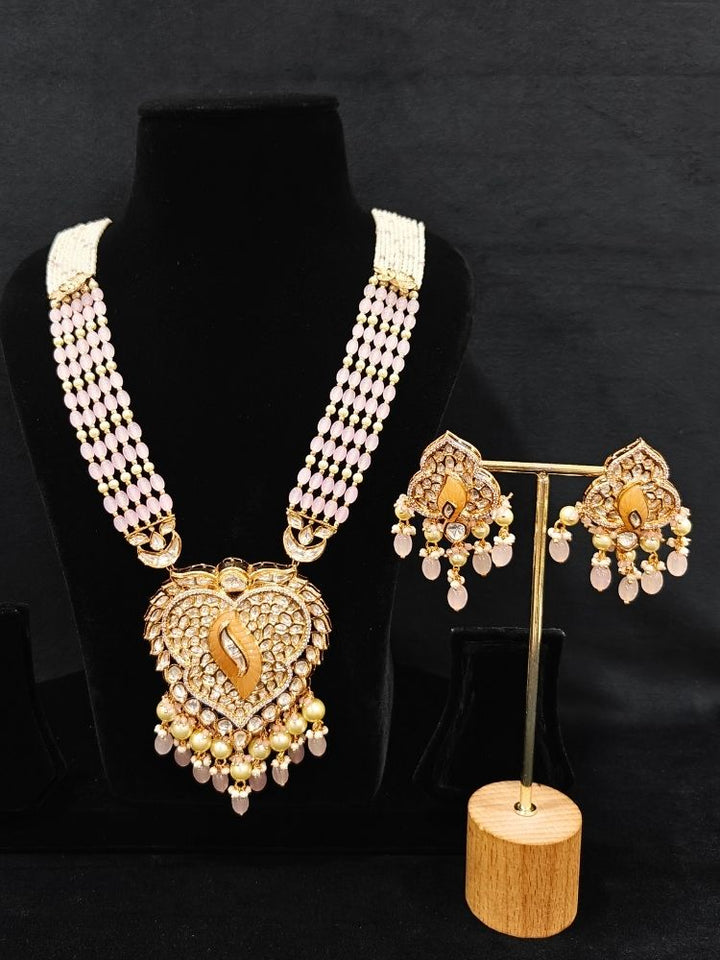 Close-up of an ornate traditional (Gold Polish) Mint Pink Long jewellery set and earrings with Polki, American Diamond Tumble Beads and Pearls. Woman wearing trending Polki artificial jewelry for the wedding season in India. Wedding guest outfit styled with an elegant Polki necklace set.