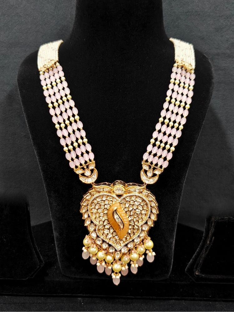 Close-up of an ornate traditional (Gold Polish) Mint Pink Long jewellery set and earrings with Polki, American Diamond Tumble Beads and Pearls. Woman wearing trending Polki artificial jewelry for the wedding season in India. Wedding guest outfit styled with an elegant Polki necklace set.