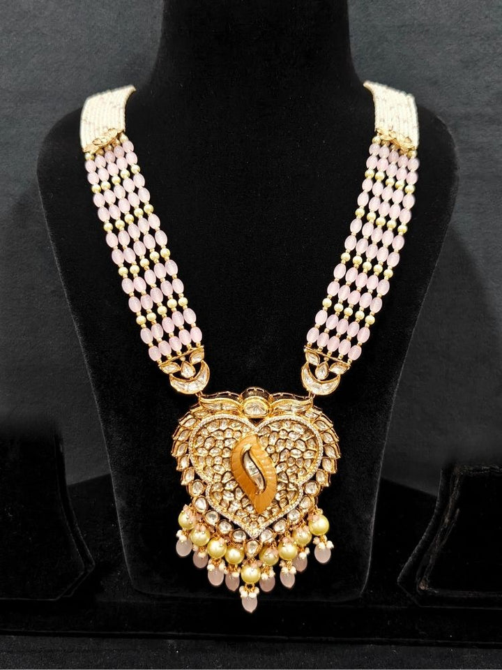 Close-up of an ornate traditional (Gold Polish) Mint Pink Long jewellery set and earrings with Polki, American Diamond Tumble Beads and Pearls. Woman wearing trending Polki artificial jewelry for the wedding season in India. Wedding guest outfit styled with an elegant Polki necklace set.