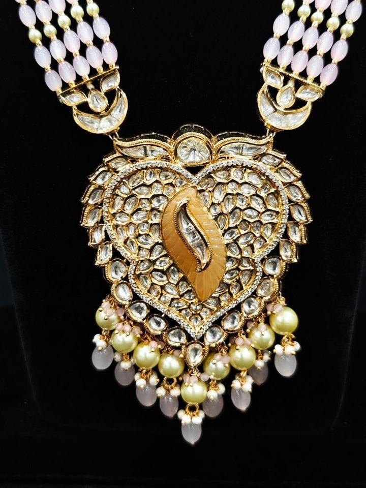 Close-up of an ornate traditional (Gold Polish) Mint Pink Long jewellery set and earrings with Polki, American Diamond Tumble Beads and Pearls. Woman wearing trending Polki artificial jewelry for the wedding season in India. Wedding guest outfit styled with an elegant Polki necklace set.