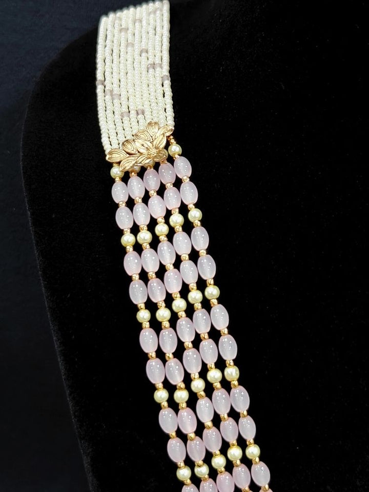 Close-up of an ornate traditional (Gold Polish) Mint Pink Long jewellery set and earrings with Polki, American Diamond Tumble Beads and Pearls. Woman wearing trending Polki artificial jewelry for the wedding season in India. Wedding guest outfit styled with an elegant Polki necklace set.