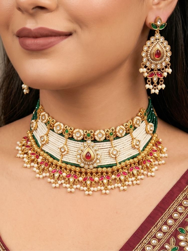 Close-up of a woman wearing an ornate traditional (Gold Polish) Choker White jewellery set and earrings with Pearl, Polki, Colored Stones, and crystal Beads. Woman wearing trending Polki artificial jewelry for the wedding season in India. Festive celebration look completed with premium imitation Polki jewelry.