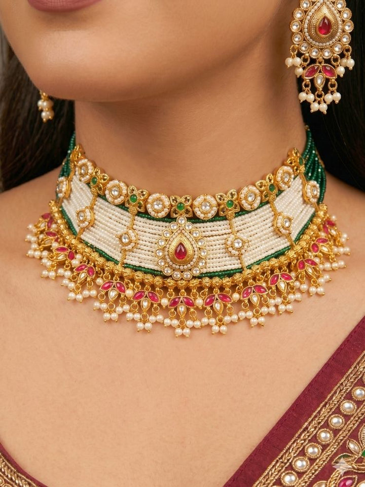 Close-up of a woman wearing an ornate traditional (Gold Polish) Choker White jewellery set and earrings with Pearl, Polki, Colored Stones, and crystal Beads. Woman wearing trending Polki artificial jewelry for the wedding season in India. Festive celebration look completed with premium imitation Polki jewelry.