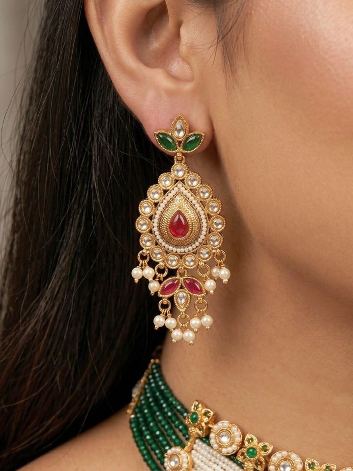 Close-up of a woman wearing an ornate traditional (Gold Polish) Choker White jewellery set and earrings with Pearl, Polki, Colored Stones, and crystal Beads. Woman wearing trending Polki artificial jewelry for the wedding season in India. Festive celebration look completed with premium imitation Polki jewelry.