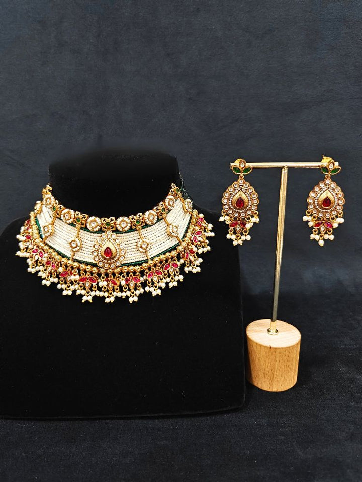 Close-up of an ornate traditional (Gold Polish) Choker White jewellery set and earrings with Pearl, Polki, Colored Stones, and crystal Beads. Woman wearing trending Polki artificial jewelry for the wedding season in India. Festive celebration look completed with premium imitation Polki jewelry.