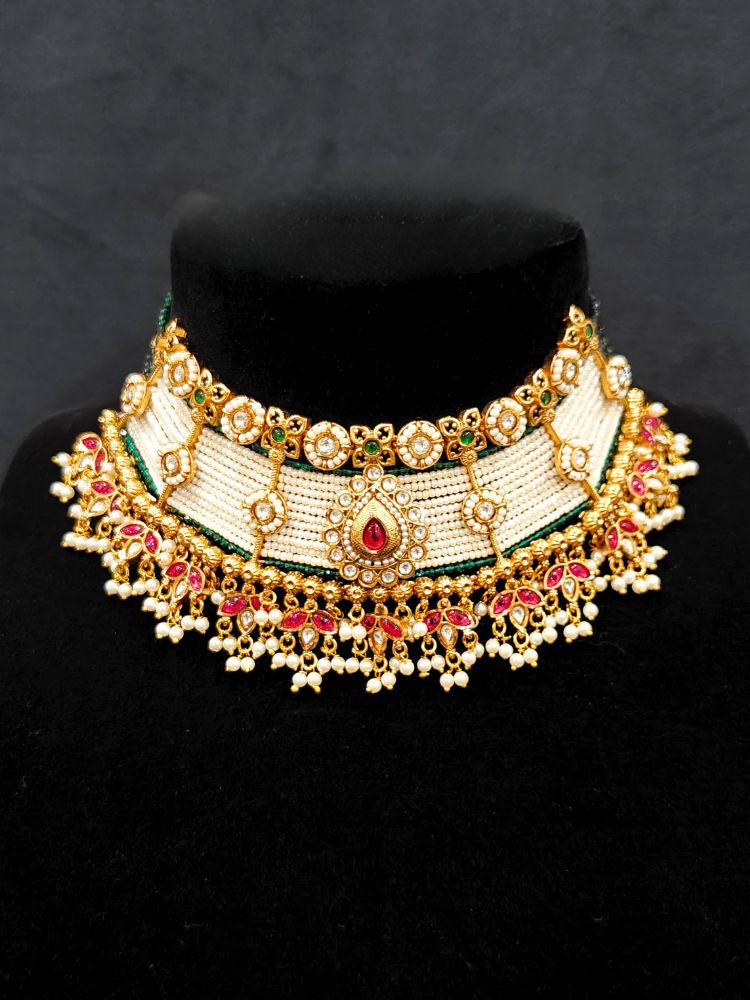 Close-up of an ornate traditional (Gold Polish) Choker White jewellery set and earrings with Pearl, Polki, Colored Stones, and crystal Beads. Woman wearing trending Polki artificial jewelry for the wedding season in India. Festive celebration look completed with premium imitation Polki jewelry.