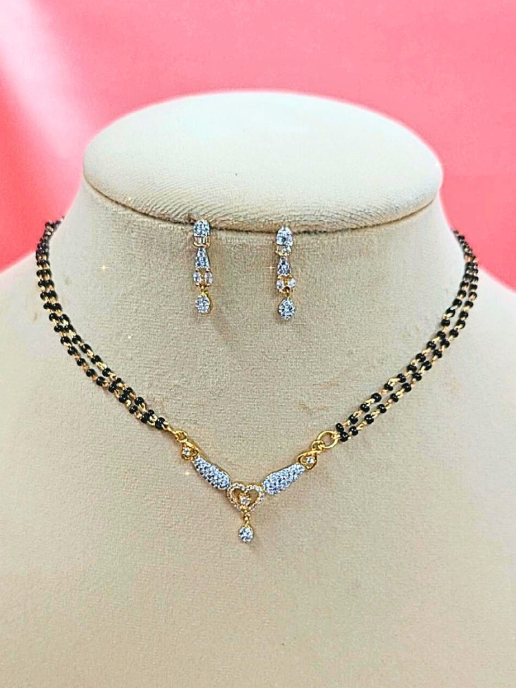  Urvashi Mangalsutra—a gold necklace with black mangalsutra beads and matching earrings, pendant featuring sparkling American Diamonds—set against a cream dummy, perfect for your wedding ceremony dress. Diamond mangalsutra. Modern mangalsutra. 