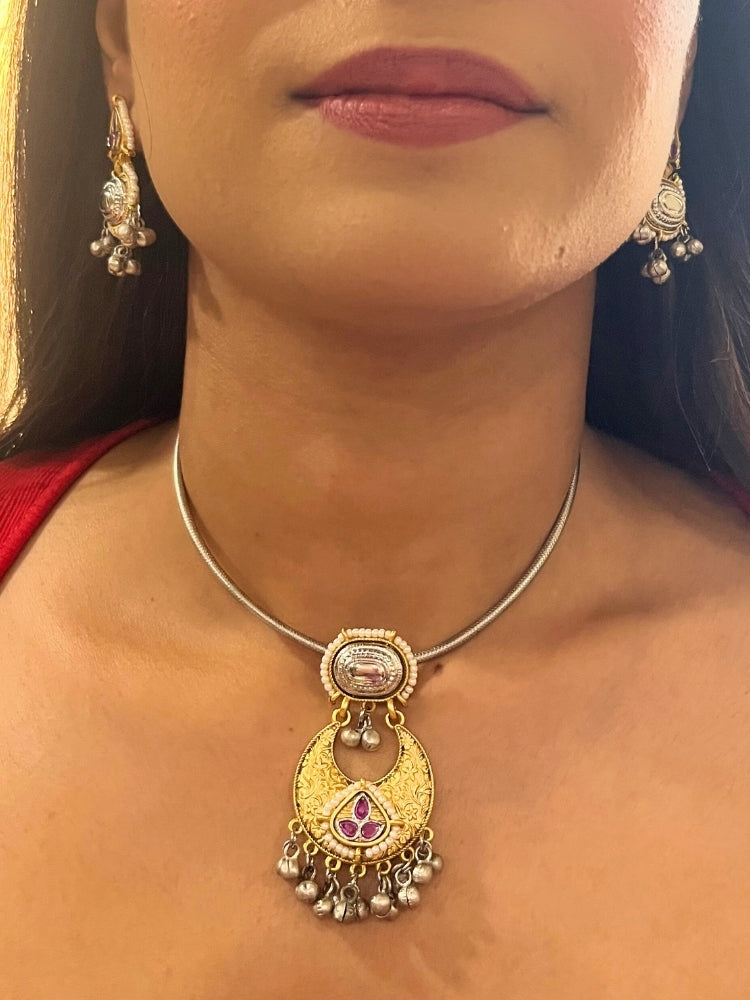 A woman wears the Usha Pink Necklace Set, featuring colored stones and matching earrings. The brass pendant oxidized necklace pops against her red top, with just her lower face, neck, and upper chest in view