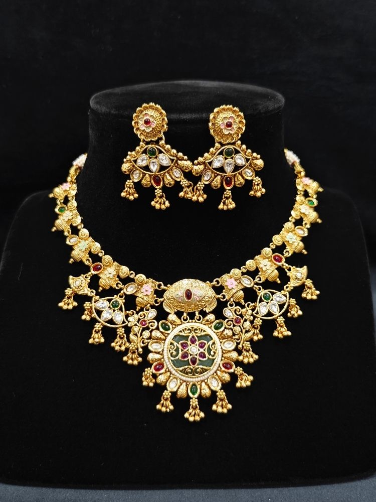 Close-up of an ornate traditional (Gold Polish) Collar jewellery set and earrings with Polki, Meenakari and Colored Stones. Festive Diwali outfit paired with a colorful Colored Stone necklace. Mehendi ceremony look completed with a Colored Stones jewelry set.