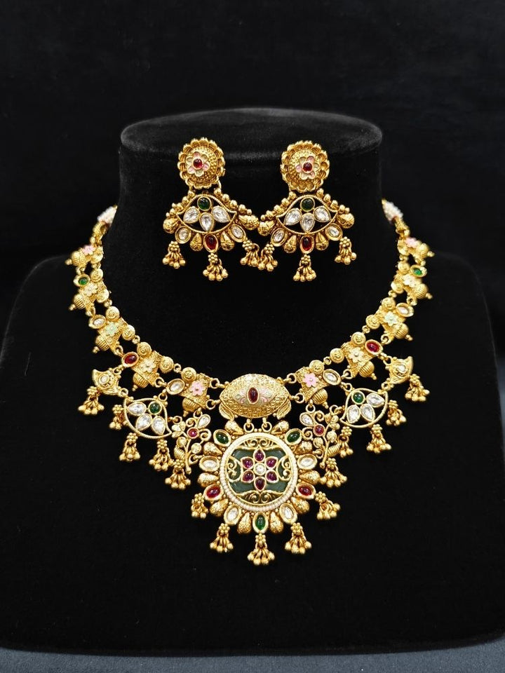 Close-up of an ornate traditional (Gold Polish) Collar jewellery set and earrings with Polki, Meenakari and Colored Stones. Festive Diwali outfit paired with a colorful Colored Stone necklace. Mehendi ceremony look completed with a Colored Stones jewelry set.