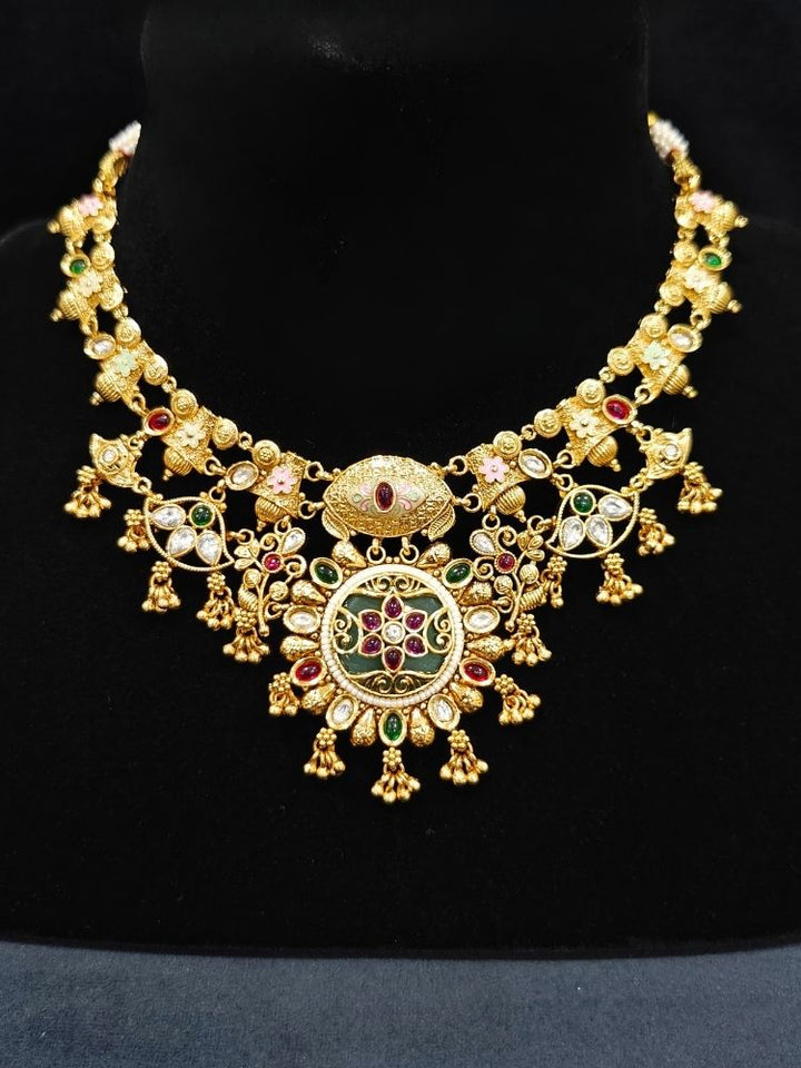 Close-up of an ornate traditional (Gold Polish) Collar jewellery set and earrings with Polki, Meenakari and Colored Stones. Festive Diwali outfit paired with a colorful Colored Stone necklace. Mehendi ceremony look completed with a Colored Stones jewelry set.