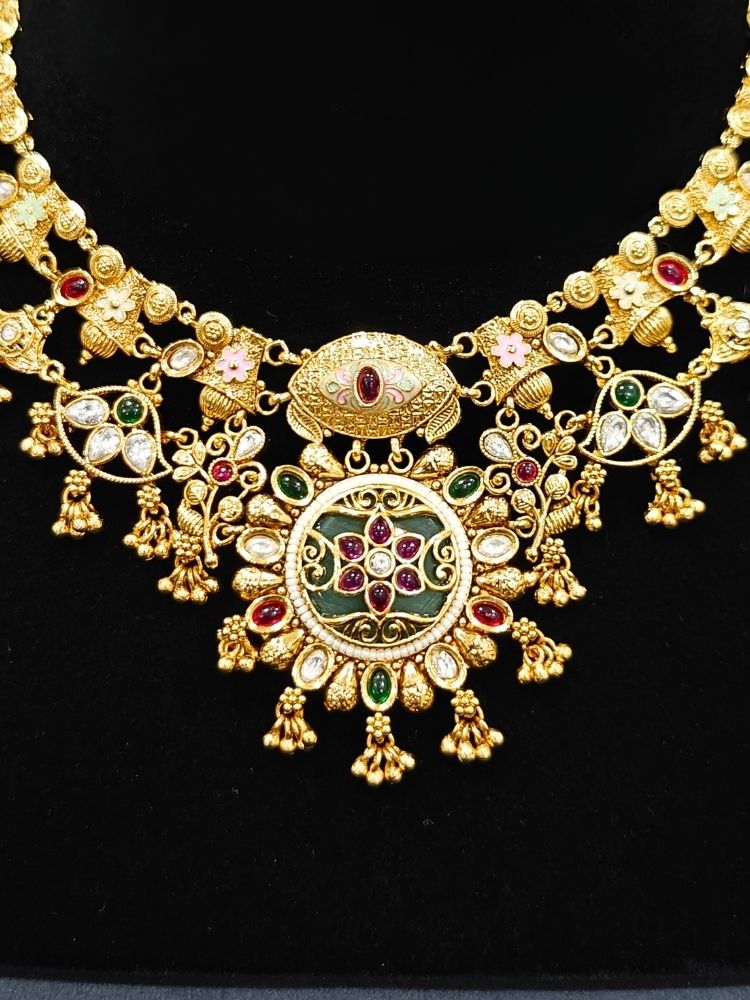 Close-up of an ornate traditional (Gold Polish) Collar jewellery set and earrings with Polki, Meenakari and Colored Stones. Festive Diwali outfit paired with a colorful Colored Stone necklace. Mehendi ceremony look completed with a Colored Stones jewelry set.
