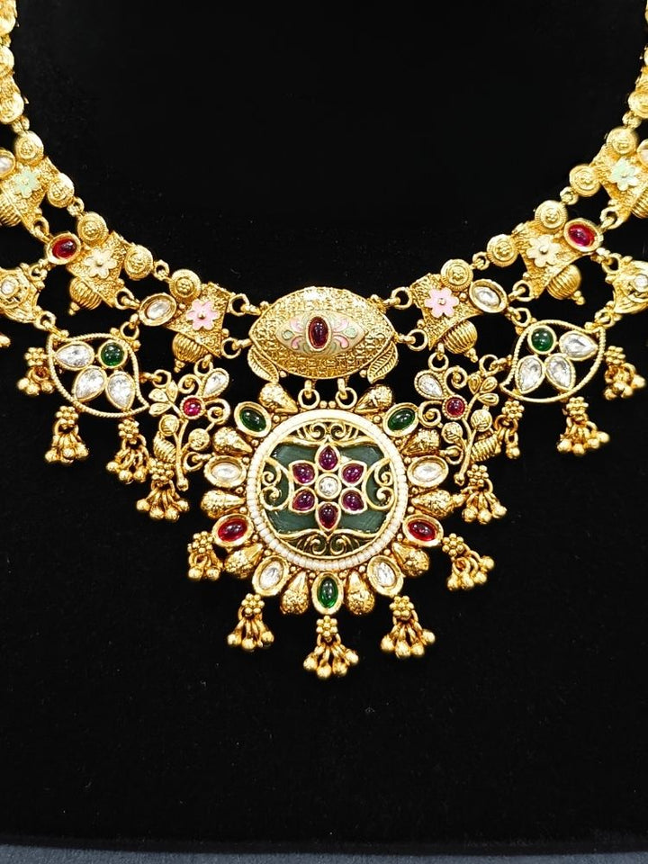 Close-up of an ornate traditional (Gold Polish) Collar jewellery set and earrings with Polki, Meenakari and Colored Stones. Festive Diwali outfit paired with a colorful Colored Stone necklace. Mehendi ceremony look completed with a Colored Stones jewelry set.