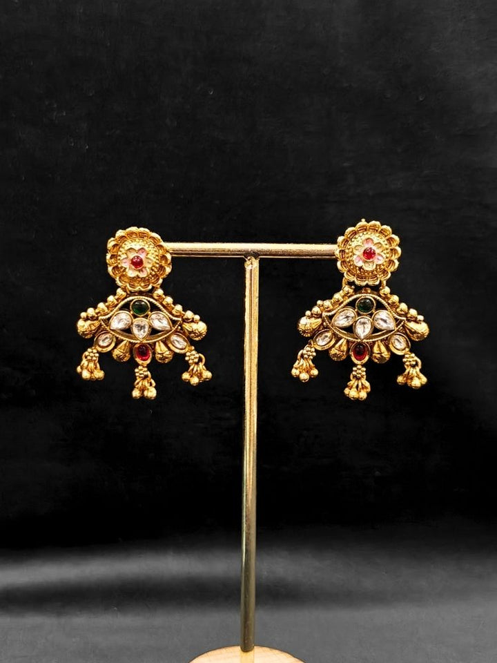 Close-up of an ornate traditional (Gold Polish) Collar jewellery set and earrings with Polki, Meenakari and Colored Stones. Festive Diwali outfit paired with a colorful Colored Stone necklace. Mehendi ceremony look completed with a Colored Stones jewelry set.