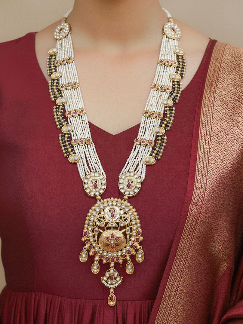 Close-up of a woman wearing an ornate traditional Rajwadi gold Long jewellery set and earrings  with  Pearls, Beads, Colored Stones, Bandhai Work and Kundan. Close-up of a Rajwadi artificial necklace for wedding celebrations. Mehendi ceremony look styled with a Rajwadi artificial jewelry set.