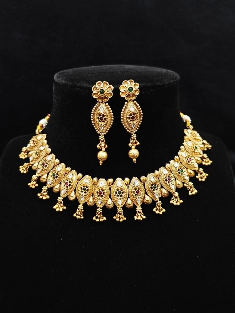 Close-up of an ornate traditional (Gold Polish) Collar jewellery set and earrings with Polki and Colored Stones. Elegant festive look with a high-quality imitation American diamond necklace set. Close-up shot of a high-quality American diamond artificial necklace worn for festive celebrations.
