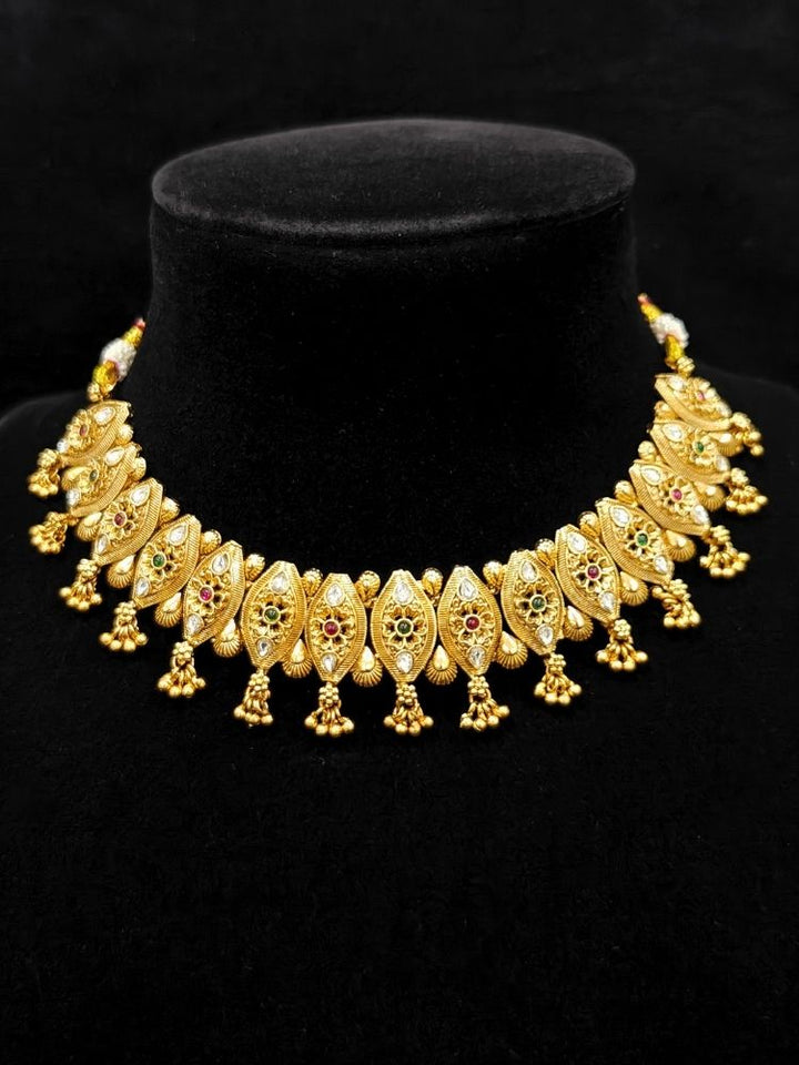 Close-up of an ornate traditional (Gold Polish) Collar jewellery set and earrings with Polki and Colored Stones. Elegant festive look with a high-quality imitation American diamond necklace set. Close-up shot of a high-quality American diamond artificial necklace worn for festive celebrations.