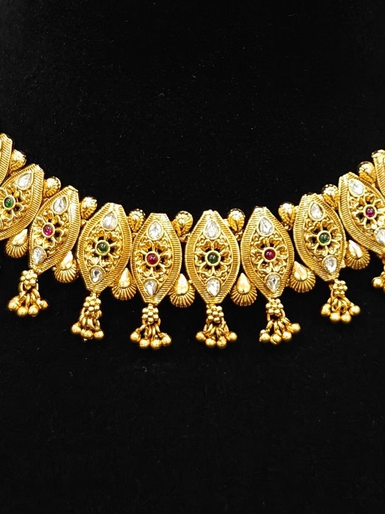 Close-up of an ornate traditional (Gold Polish) Collar jewellery set and earrings with Polki and Colored Stones. Elegant festive look with a high-quality imitation American diamond necklace set. Close-up shot of a high-quality American diamond artificial necklace worn for festive celebrations.