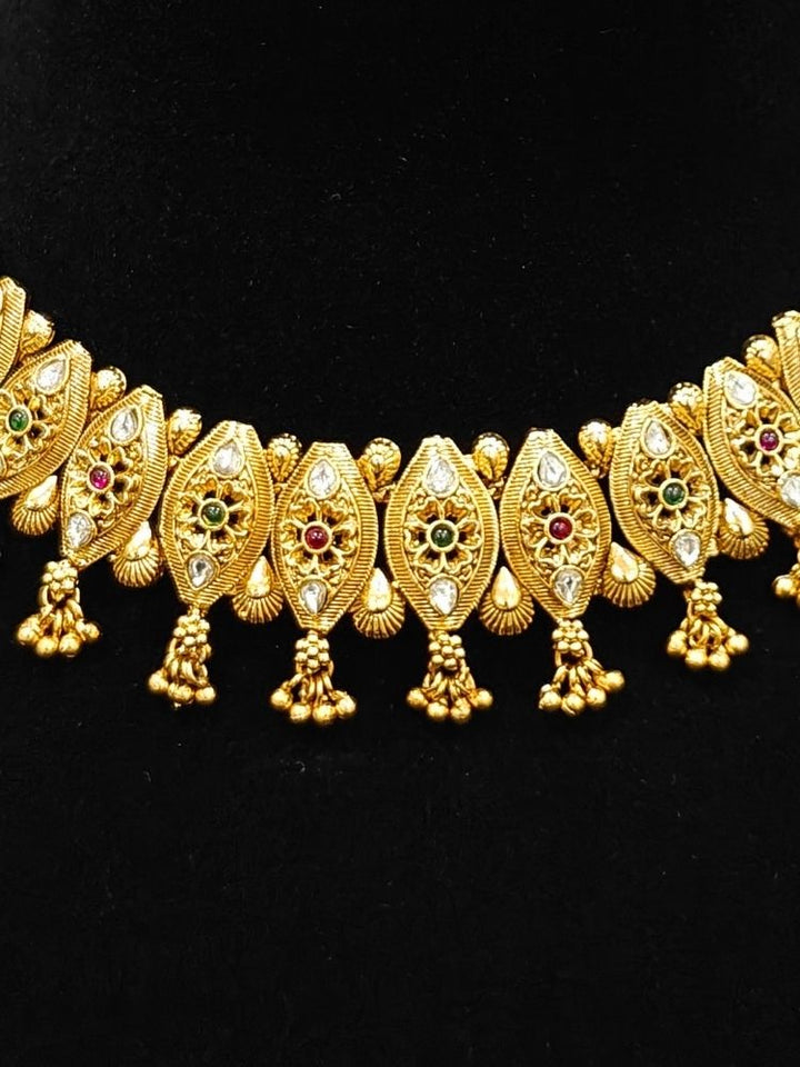 Close-up of an ornate traditional (Gold Polish) Collar jewellery set and earrings with Polki and Colored Stones. Elegant festive look with a high-quality imitation American diamond necklace set. Close-up shot of a high-quality American diamond artificial necklace worn for festive celebrations.