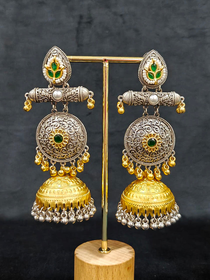A close-up of Varnika Green Earrings, ornate gold and silver with floral designs, colored stones, dangling silver beads, and a large intricate jhumka dome at the bottom. Long Oxidized earrings, german silver earrings, navratri earrings.  Jhumka earrings. Jhumki Earrings. 