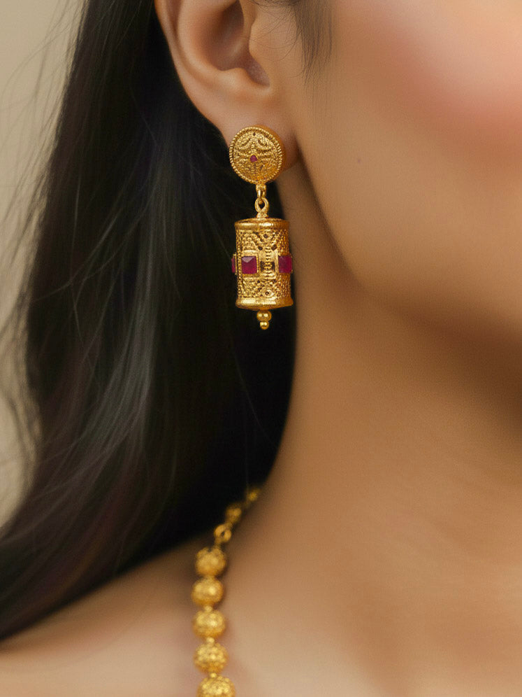 Close-up of a woman wearing an ornate traditional (Bright Gold Polish) Long Jewellery Set with Earrings with Ruby Red Colored Stones and Filigree Work. Saree look completed with an elegant Colored Stone artificial jewelry piece. Woman wearing trending Colored Stone artificial jewelry for wedding season in India.