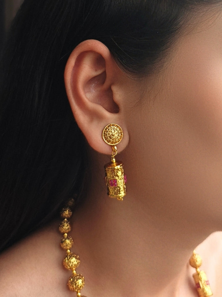 Close-up of a woman wearing an ornate traditional (Bright Gold Polish) Long Jewellery Set with Earrings with Ruby Red Colored Stones and Filigree Work. Saree look completed with an elegant Colored Stone artificial jewelry piece. Woman wearing trending Colored Stone artificial jewelry for wedding season in India.