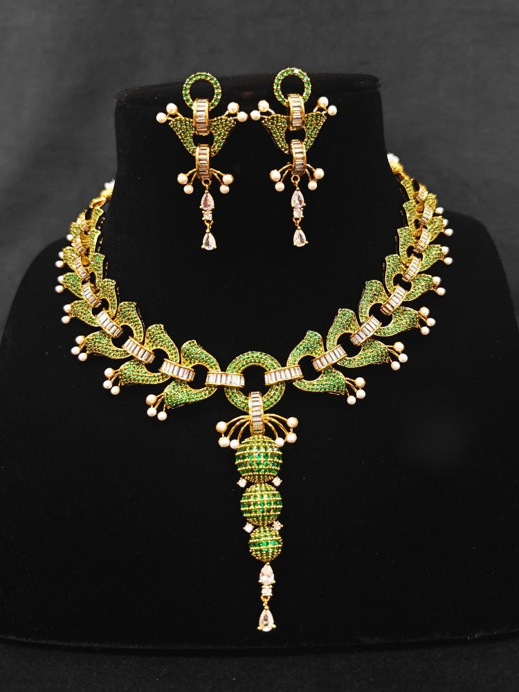 Close-up of an ornate Indo-Westerrn Green Collar jewellery set and earrings with Green Colored Stones, Baguette American Diamonds and Pearls. Reception party styling featuring a premium Colored Stones imitation set. Close-up of a cocktail party look featuring a premium Colored Stones necklace.