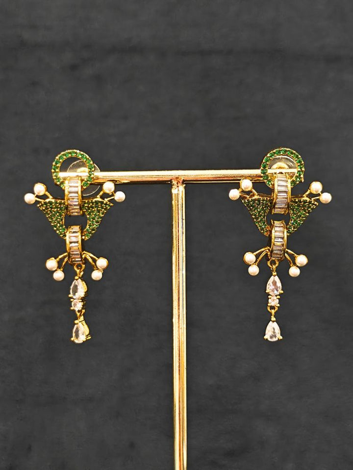 Close-up of an ornate Indo-Westerrn Green Collar jewellery set and earrings with Green Colored Stones, Baguette American Diamonds and Pearls. Reception party styling featuring a premium Colored Stones imitation set. Close-up of a cocktail party look featuring a premium Colored Stones necklace.