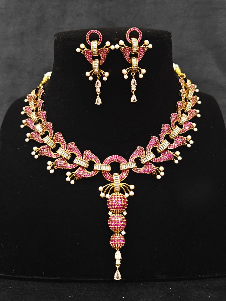 Close-up of an ornate Indo-Westerrn Pink Collar jewellery set and earrings with Pink Colored Stones, Baguette American Diamonds and Pearls. Reception party styling featuring a premium Colored Stones imitation set. Close-up of a cocktail party look featuring a premium Colored Stones necklace.