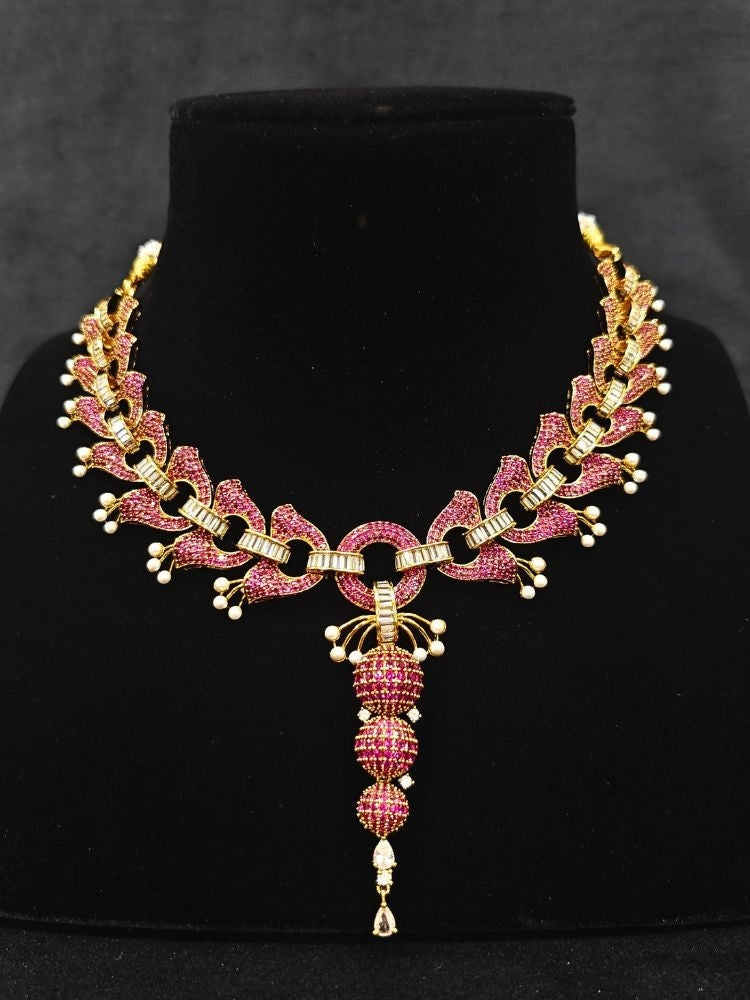 Close-up of an ornate Indo-Westerrn Pink Collar jewellery set and earrings with Pink Colored Stones, Baguette American Diamonds and Pearls. Reception party styling featuring a premium Colored Stones imitation set. Close-up of a cocktail party look featuring a premium Colored Stones necklace.