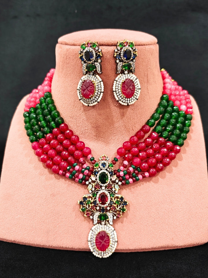 Close-up of a woman wearing an ornate traditional Colored Stones Multi-Color gold Collar jewellery set and earrings with Colored Beads, Colored Stones and American Diamond. A luxury Colored Stones necklace set styled beautifully for a wedding guest look in India. Elegant festive look with a high-quality imitation Colored Stones necklace set.