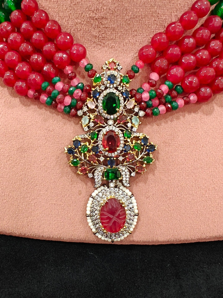Close-up of a woman wearing an ornate traditional Colored Stones Multi-Color gold Collar jewellery set and earrings with Colored Beads, Colored Stones and American Diamond. A luxury Colored Stones necklace set styled beautifully for a wedding guest look in India. Elegant festive look with a high-quality imitation Colored Stones necklace set.
