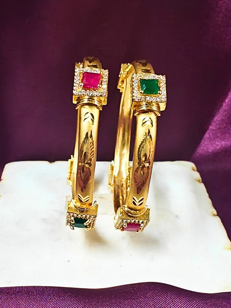 Close-up of an ornate traditional (Gold Polish) Bangles Set with American Diamond and Pink & Green Colored Stone. Festive celebration look enhanced with artificial Colored Stone bangles. Close-up of premium imitation Colored Stone bangles styled with a silk saree.